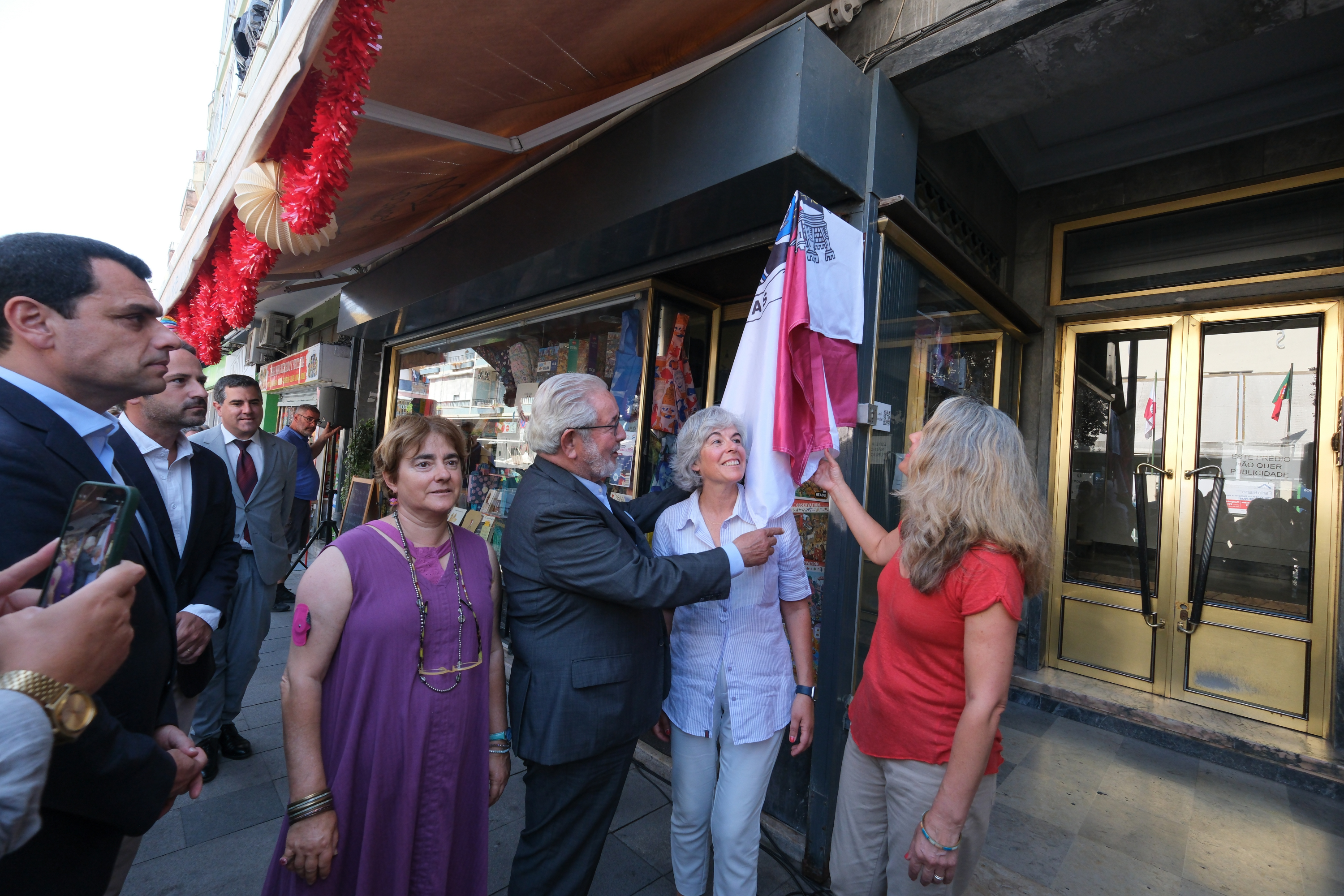 Fotografia do Presidente CMO com as proprietárias da loja., a descerrar a placa 'Loja com história'. 