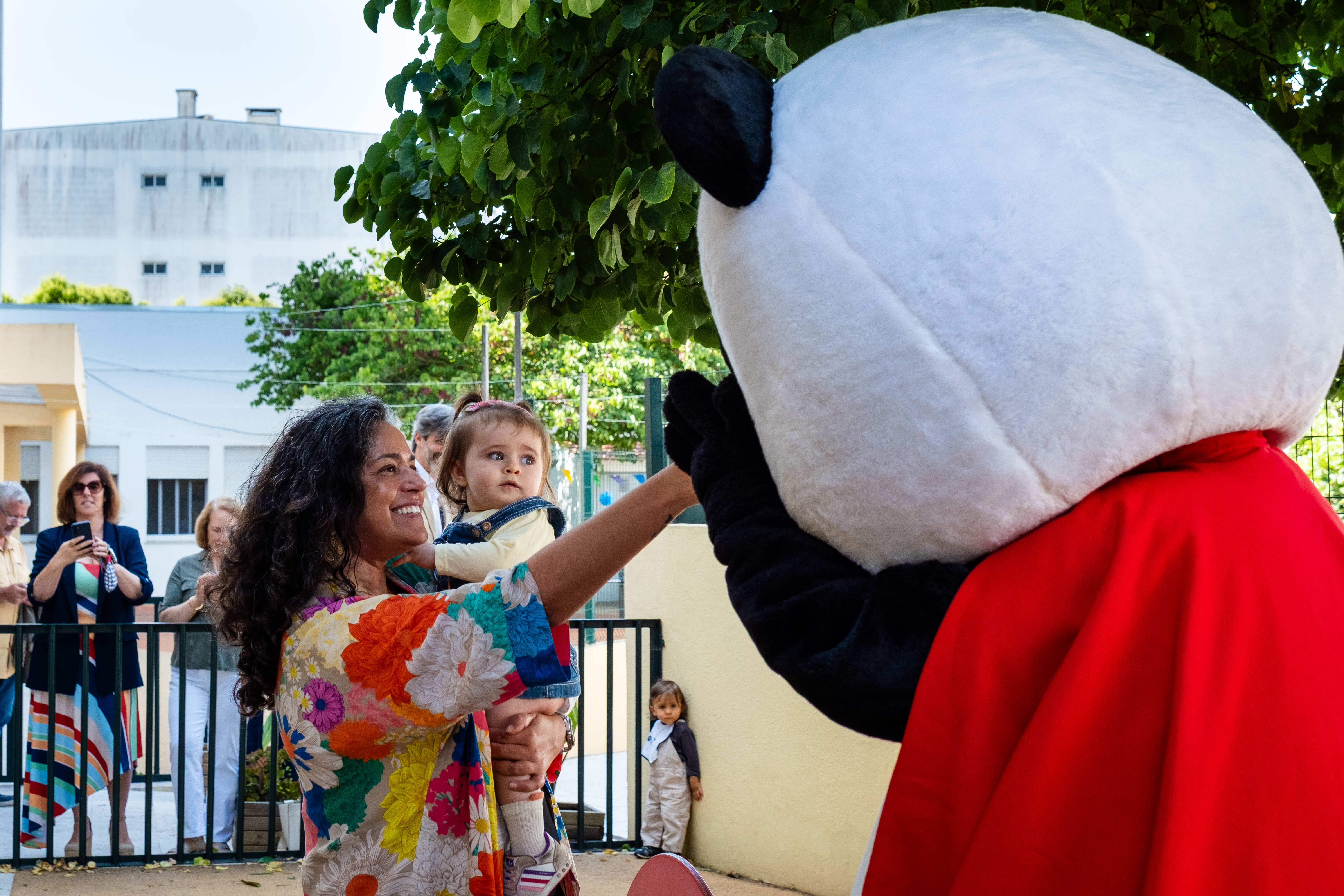 Vereadora Carla Rocha, com uma criança ao colo a cumprimentar o Panda. 